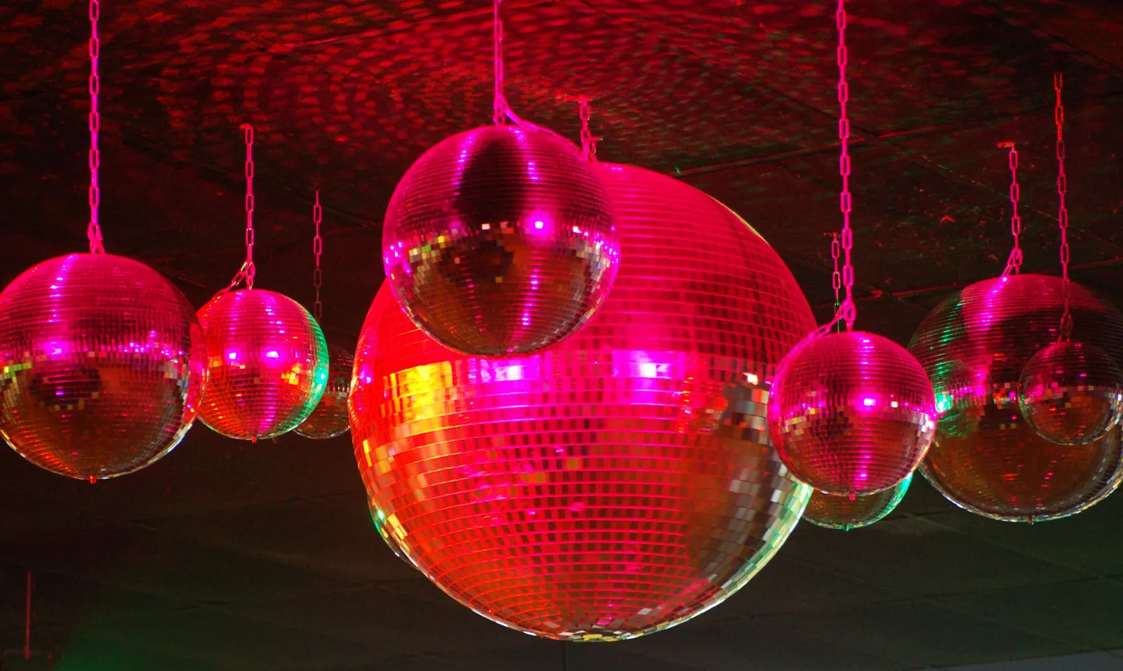 multiple disco balls hanging from the ceiling in red lighting